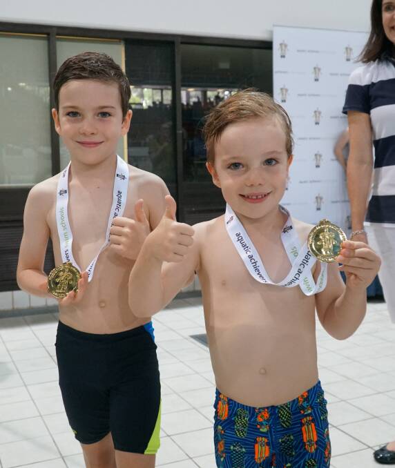 CONQUERED:  Jack and Tom Gorry couldn't be prouder to receive their gold medals after victoriously completing a 1km swim. Photos: Pejman Talebi