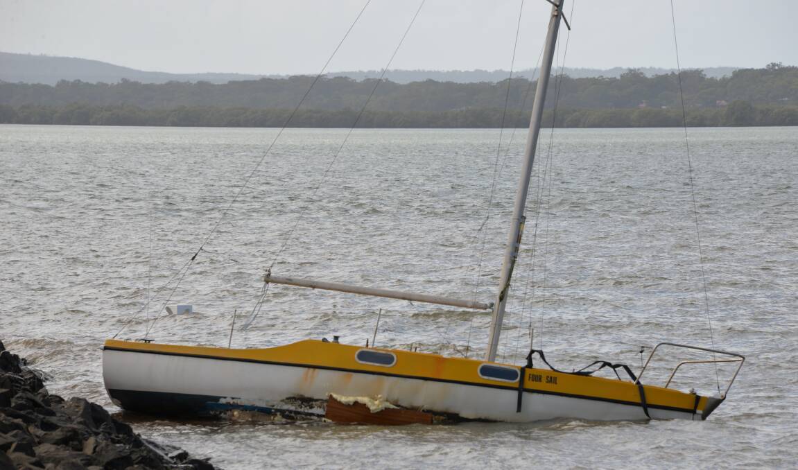heavy conditions: A yacht that broke moorings aground and holed on a rock wall at Weinam Creek.