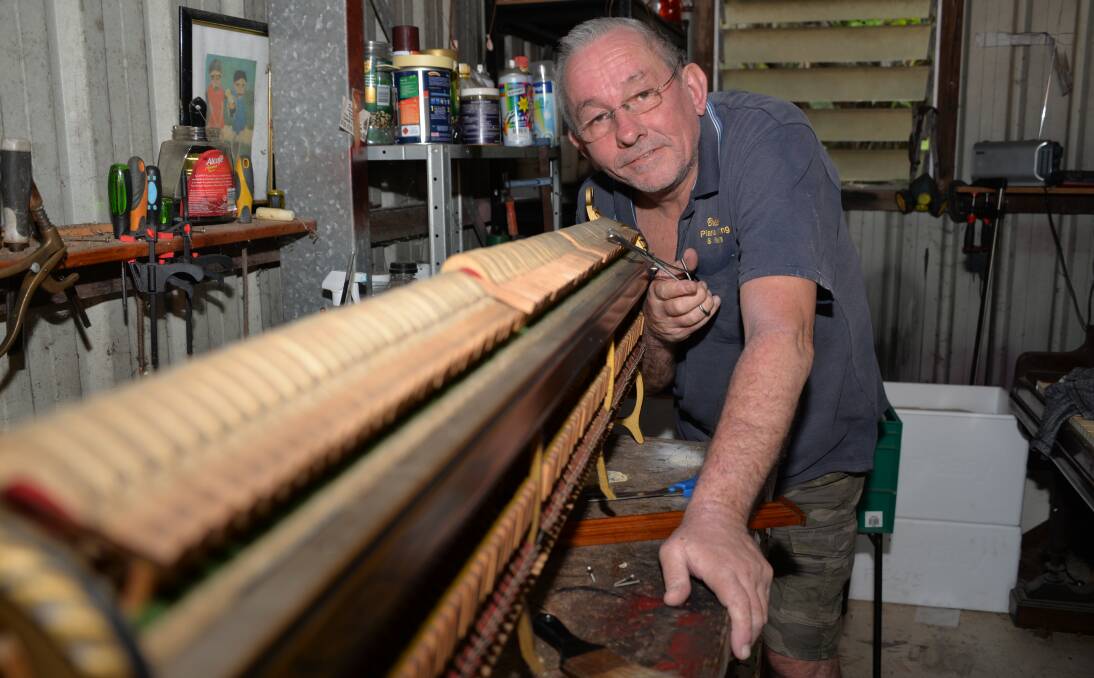 ON SONG: Piano repairer Dan Ling working on pianos inside his shed at Alexandra Hills.
