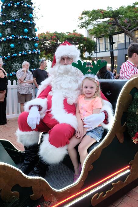 CHRISTMAS FUN: Libby Tranter, 4, with the man in red and that big tree in the background.