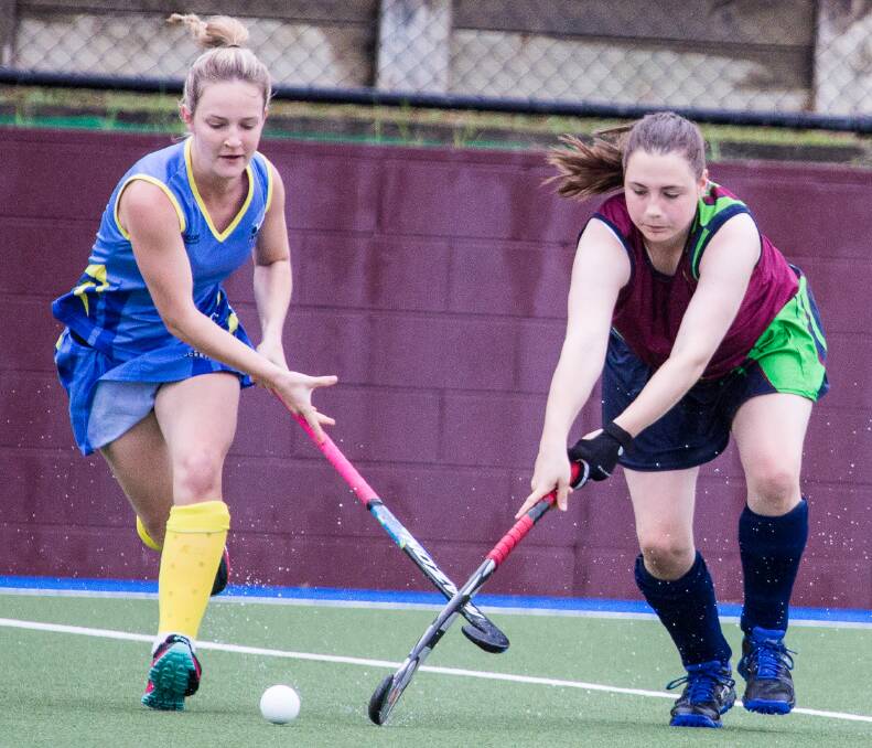 hockey battle: Cairns player Simone Bettany and Charlotte Schenkluhn of Redlands. Picture: Andrew Blanchard.
