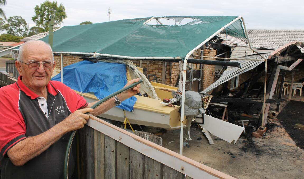 FIGHTING FIRE: Neighbour Ervin Ferris used a hose to try and stop the fire spreading to a boat and shed. Photo: Cheryl Goodenough