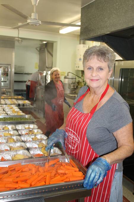 VOLUNTEERS: Anne Piggott dishes food at Meals on Wheels Capalaba. In the background is Deborah Stengord. Photo: Cheryl Goodenough