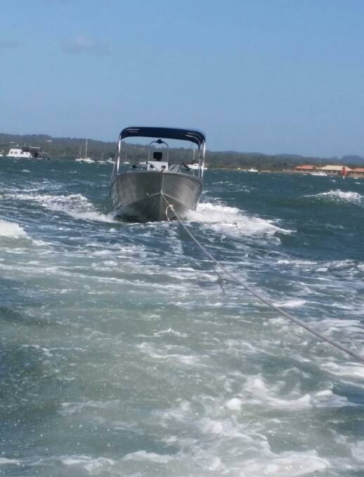 Towed: An aluminium boat is towed to safety near Coochiemudlo Island on Sunday. Photo: Redland Bay Coast Guard