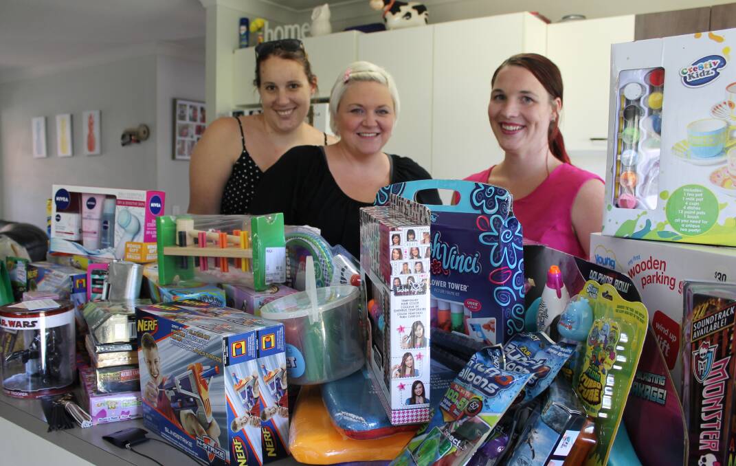 OVERWHELMED: Lyndal Odgaard, Brooke Morgan and Sienna Kinnear with some of the presents donated to help five Redlands families have a happier Christmas. Photo: Cheryl Goodenough