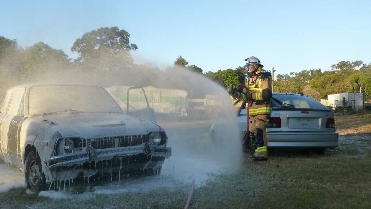 HELPING OUT: An auxiliary firefighter extinguishes a car fire. Photo: Queensland Fire and Emergency Services