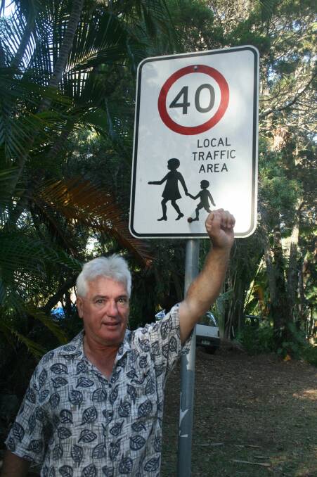 Russell Jackson with one of the 40km/h signs on Coochiemudlo Island, where residents want to use electricgolf buggies on the road.