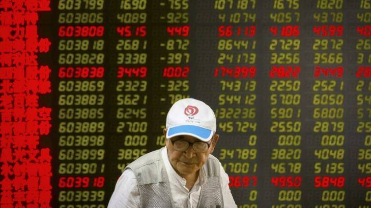 A Chinese investor walks past displays of stock information at a brokerage house in Beijing.  Photo: Mark Schiefelbein