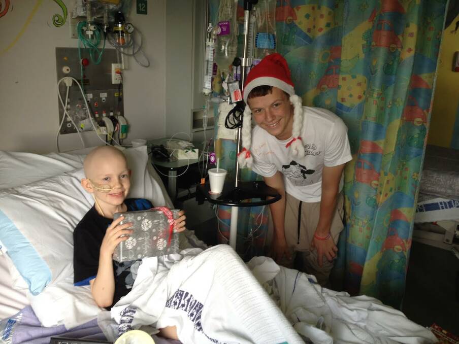 Luke Spalding, right, has a rare and agressive form of cancer, and it has spurred him on to help other sick children. For the second consecutive year, Luke is raising money to buy iPads for children with cancer who will be in hospital on Christmas Day. Luke is pictured giving young cancer patient, Devlin, an iPad on Christmas Day last year.