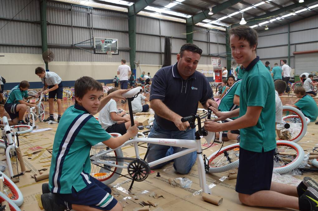 DOWN to work fixing up this bike at the Happiness Cycle are students Ben Lindborg (left) and Ricky Precoma with Redland City Council officer Byron Shreeve.