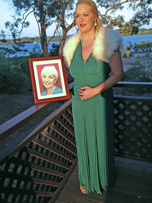 Macleay Island model Iona Marcon, with a photograph of her boss Debi Dingwell, who died after a battle with cancer. Iona will model some of the garments at the parade, which will raise money for breast cancer research.