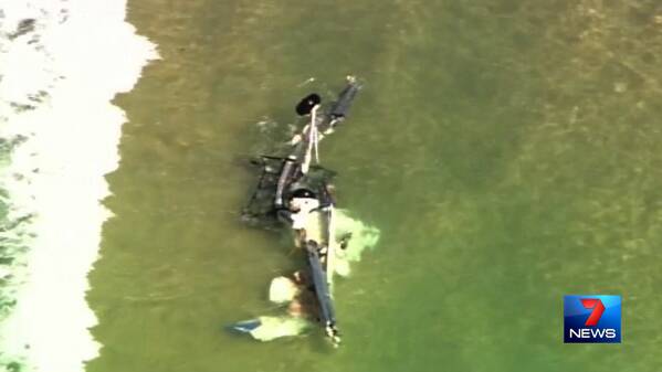 The wreckage of the ultralight plane in shallow water, just south of Point Lookout on North Stradbroke Island.  Photo Seven News