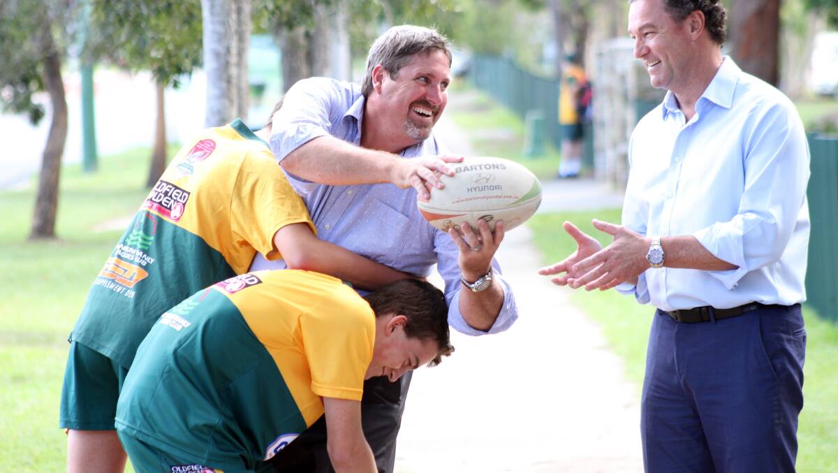 Capalaba MP Steve Davies offloads the ball to State education minister John-Paul Langbroek as Alexandra Hills State School students Max Baumer, 14 and Joseph Lewis, 14 apply a tackle.
Photo by Chris McCormack
