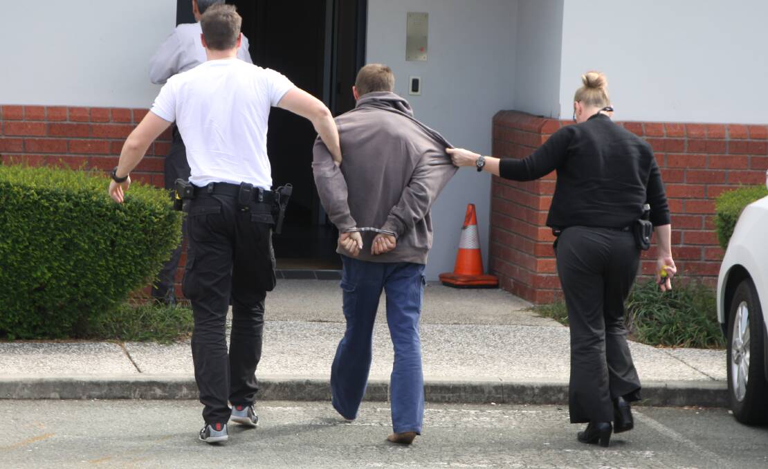 Detectives escort a 28-year-old man arrested over a Wynnum West home invasion into Cleveland Police Station on Wednesday afternoon. Photo by Stephen Jeffery