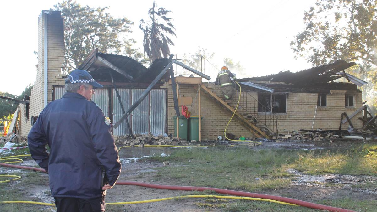 Redland Bay senior constable Kim Ensinger at the site of the fire which gutted this two-storey brick house at Redland Bay. The
fire started while the family fo 10 was away on holidays. Firies have issued warnings to those going away for holidays to unplug
all electrical equipment. Photo by Judith Kerr