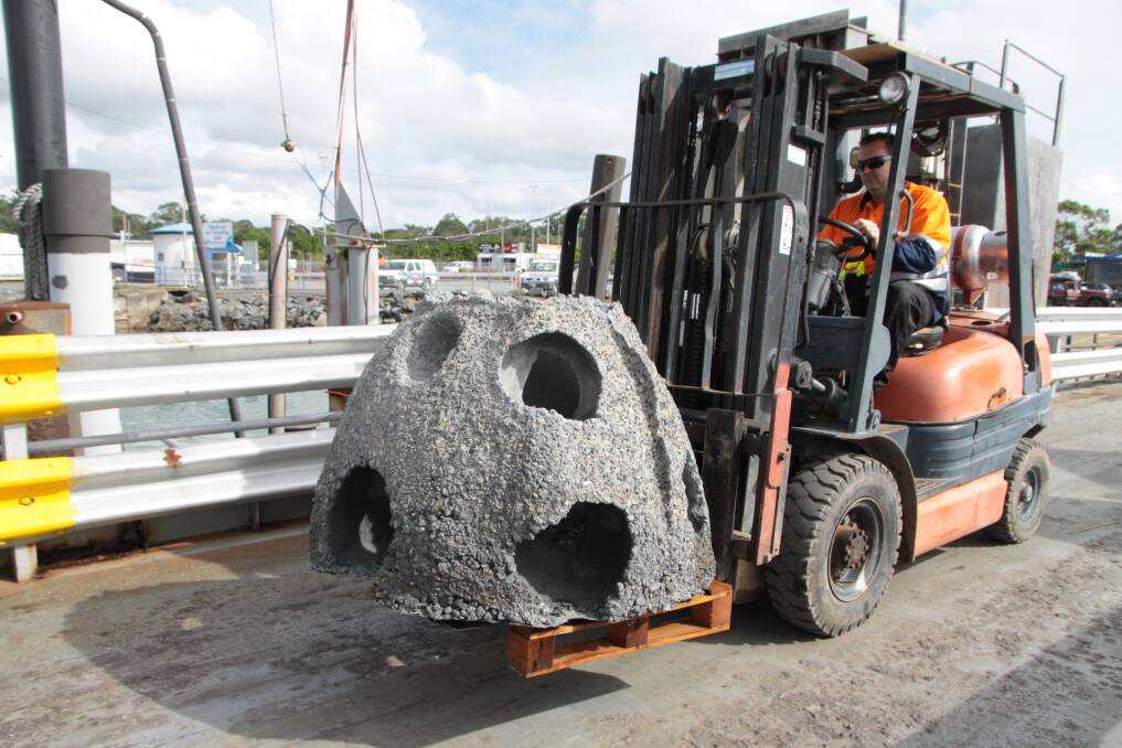 STEP 1: A forklift carries one of the 600kg concrete fish balls on to the deck of a Straddie Ferries barge. Photos: Chris McCormack