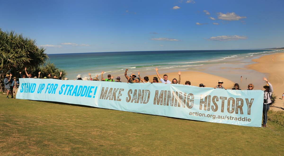 Australian Conservation Foundation members unfurl a banner on Main Beach this morning protesting sand mining on North Stradbroke Island. Photo: ACF