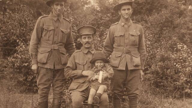 Algernon Cook (seated) holds an unknown child before sailing away from the Redlands to the distant battles of Worid War I. Photo: Australian War Memorial - P10452.003