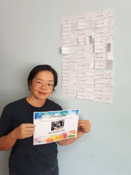 COMMUNITY SPIRIT: Bay Breeze Cafe owner Jenny Tan with some of the food vouchers donated by cafe customers.