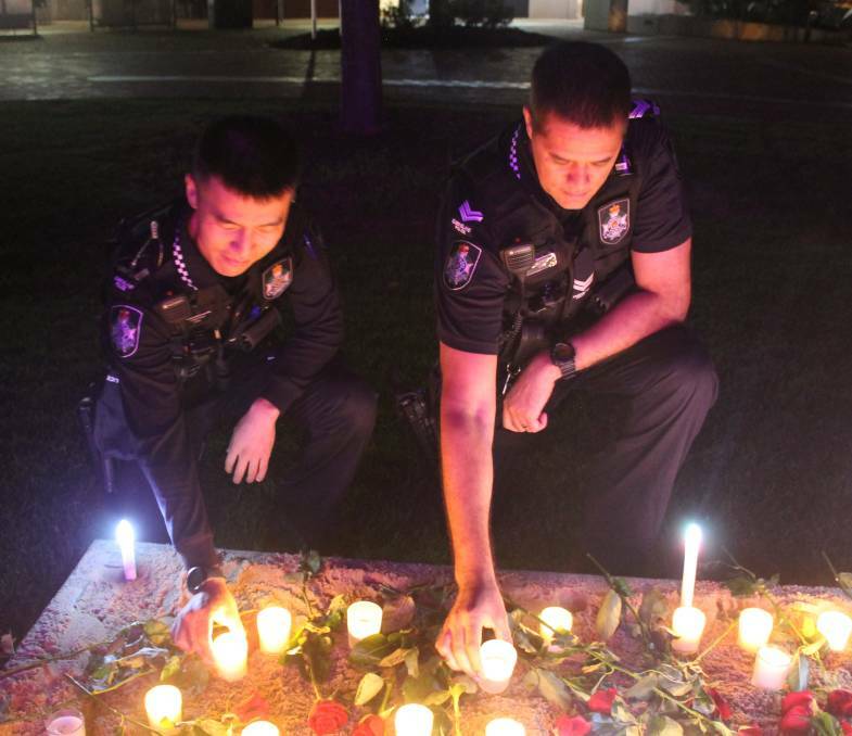 REMEMBER: Constable Chenzhi Gao and Senior Constable Wiremu Willis place lighted candles at the vigil at Raby Bay at last year's vigil.