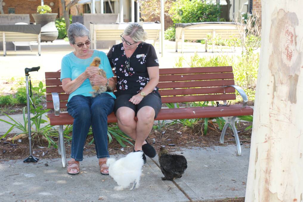 OUTDOORS: Moreton Shores resident Jan with diversional therapist Bec McLeod help look after the facility's chooks. 