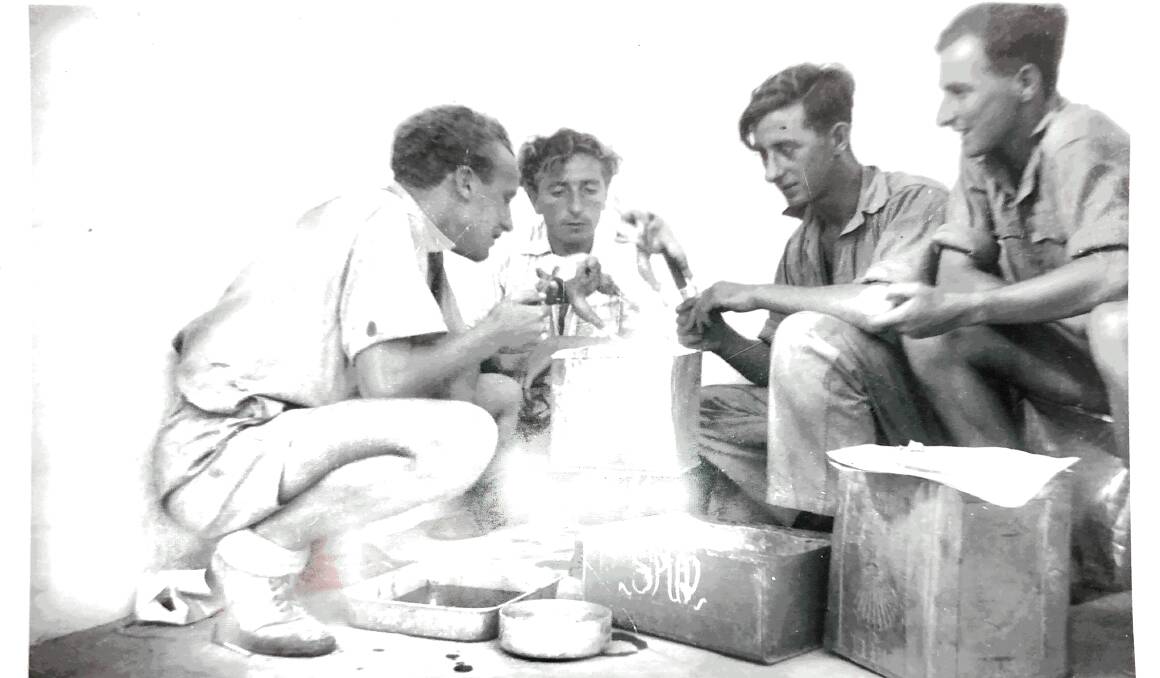 NORTH AFRICA: Harry Gardiner (second from left) eats a meal with mates. Sand and petrol were put into a tin which became a makeshift stove.
