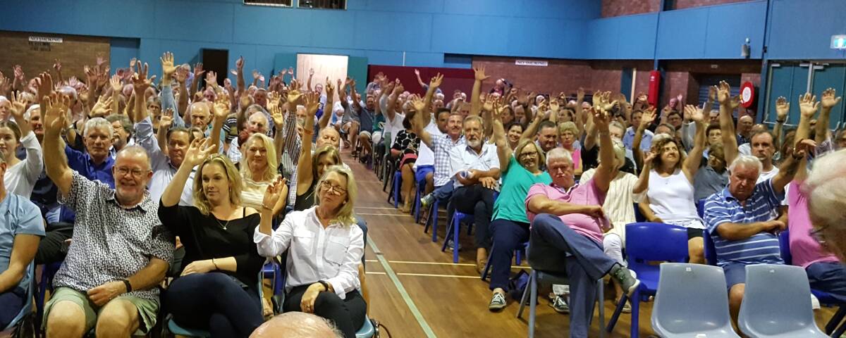 HANDS UP: Raby Bay residents vote at a meeting called to discuss Redland City Council funding of canal repairs.