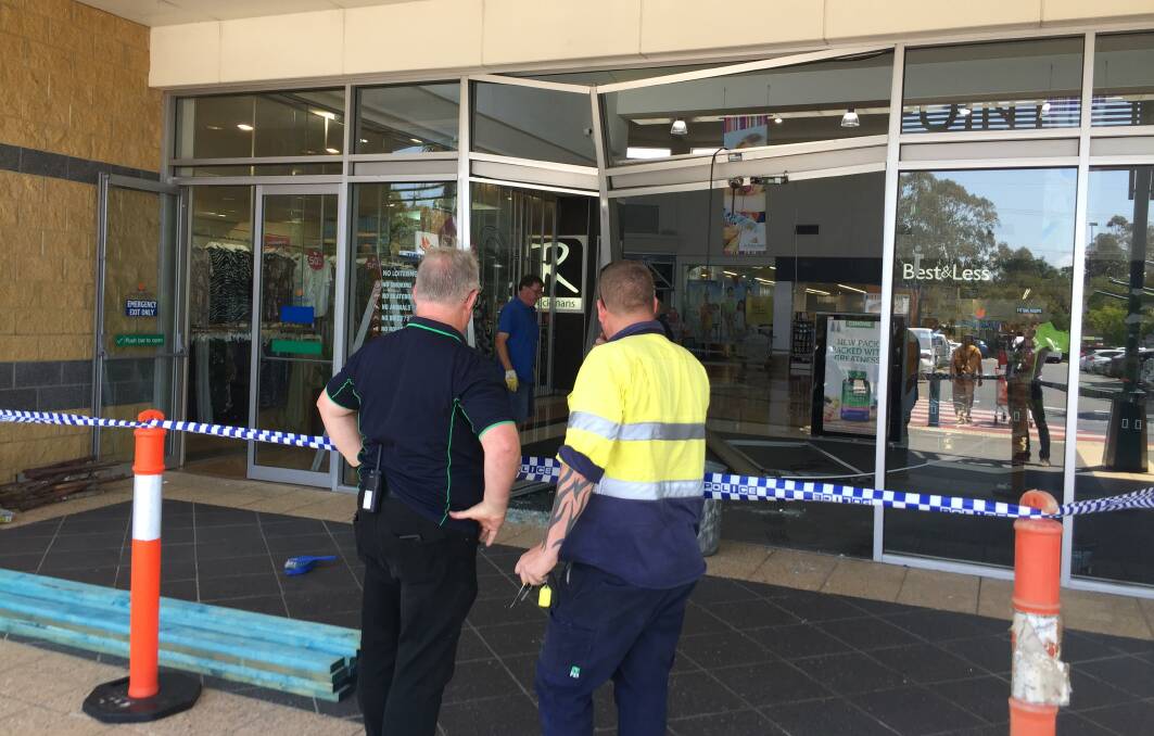 RAM RAID: Workmen at the site of the raid that did significant damage to the front of the shopping centre. Photo: Jordan Crick. 