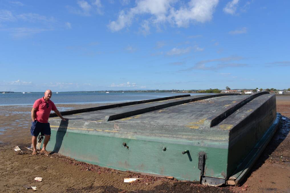 BARGE ASHORE: Victoria Point resident James Dunlevie at the barge which came ashore in strong winds about three months ago.