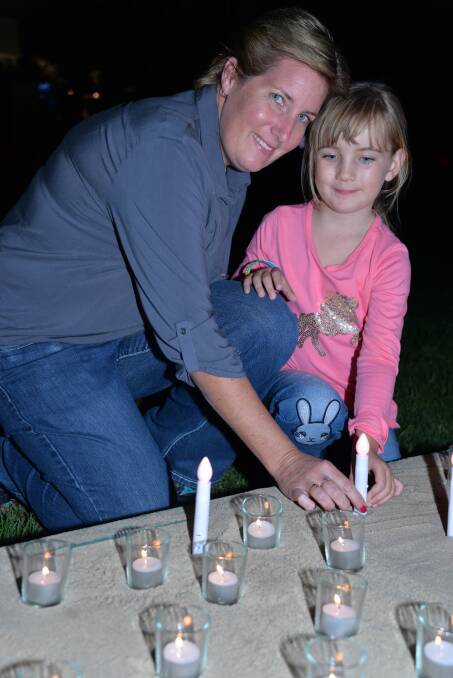 vigil visitors: Carly Shreeve of Capalaba and daughter Riley, 5, light a candle.