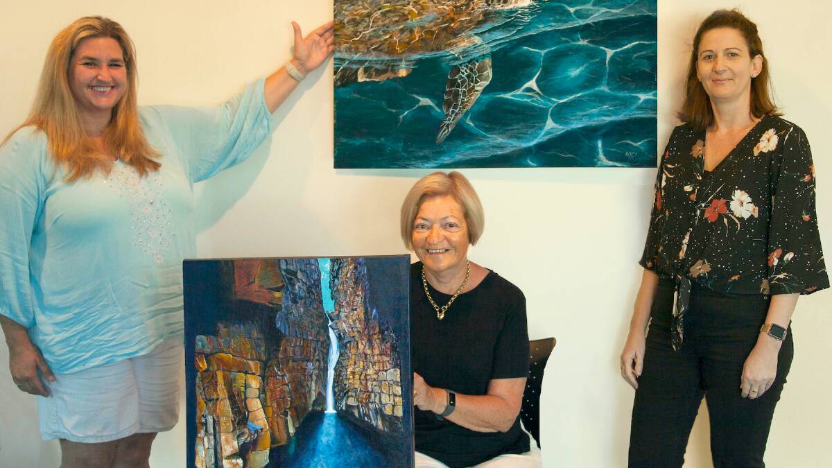 Keeping their distance: Nicci Bickley with her painting Turtle Surfacing, Cheryl Reynolds with her painting The Water Cave and Megan Imber, acting manager RPAC.