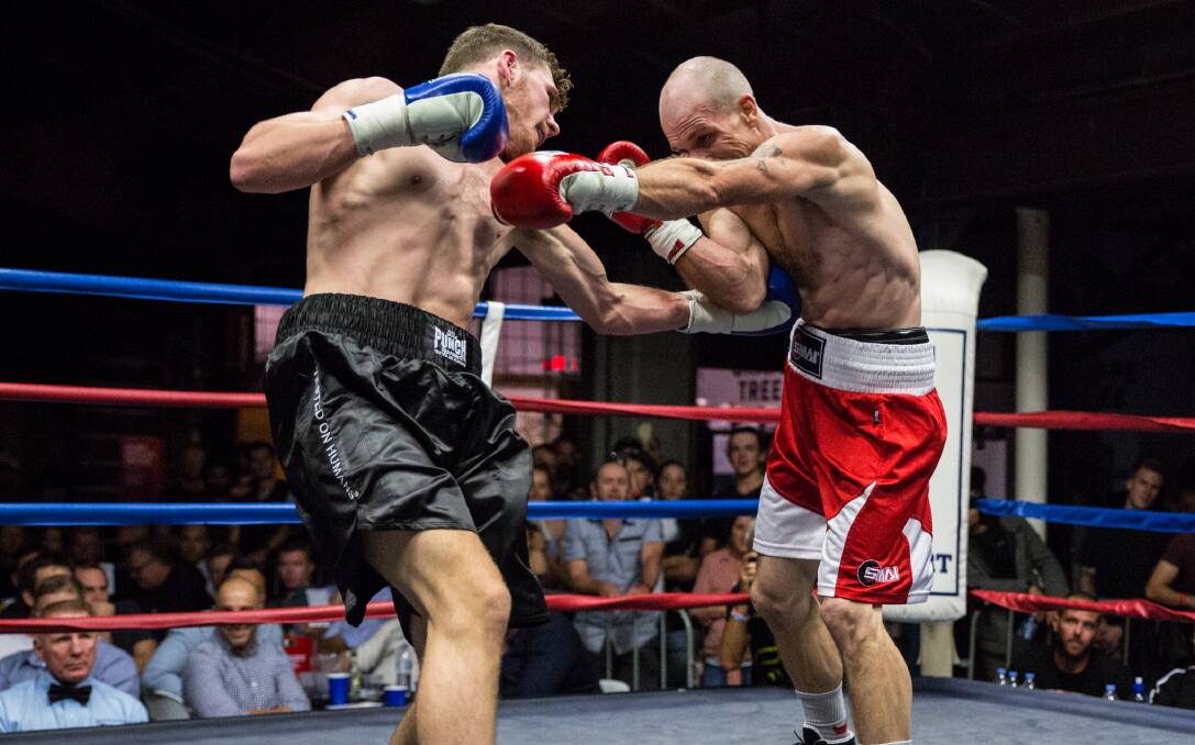 FULL BLOODED: Michael Black and Gary Ross battle it out in the junior welterweight main card. Photo: Adam Winterbottom