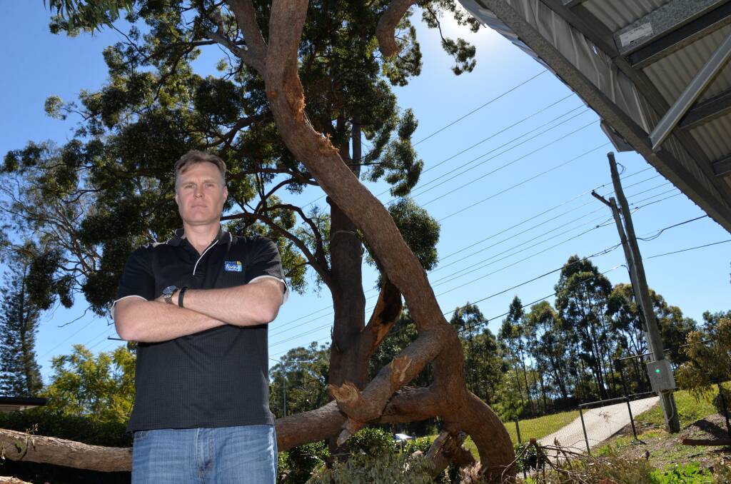 DAMAGE DONE: Brendan Key and the massive tree limb that crashed on to his carport from a neighbour's front yard on Redland Bay Road.