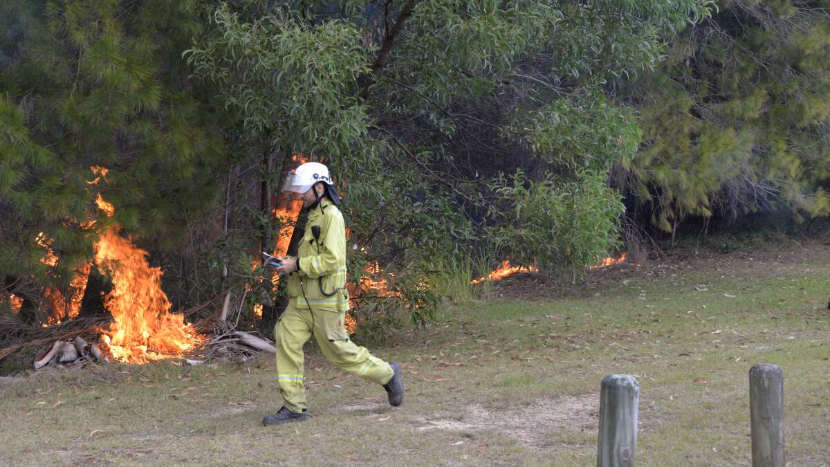 RESIDENTIAL MADNESS: A worker monitors a blaze as dangerous piles of rubbish dumped at the back of homes in the Scribbly Gums Conservation Reserve goes up.