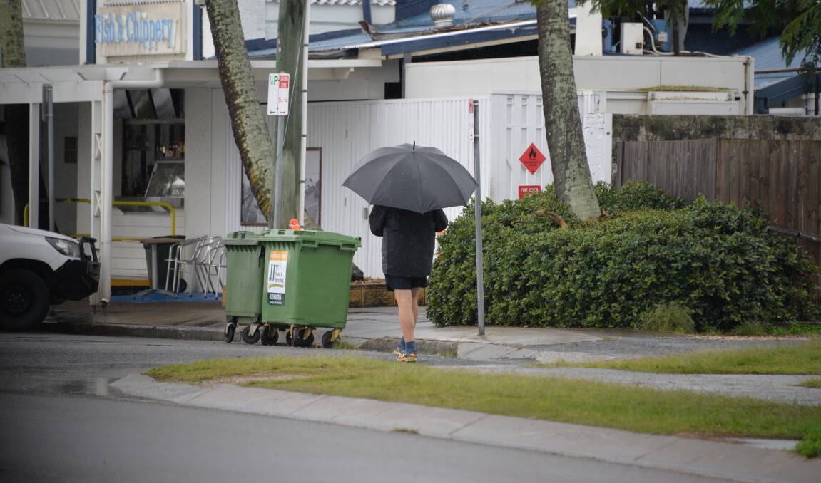 WILD WEATHER: A man walks at Cleveland point during a downpour earlier this year. Photo: Jordan Crick