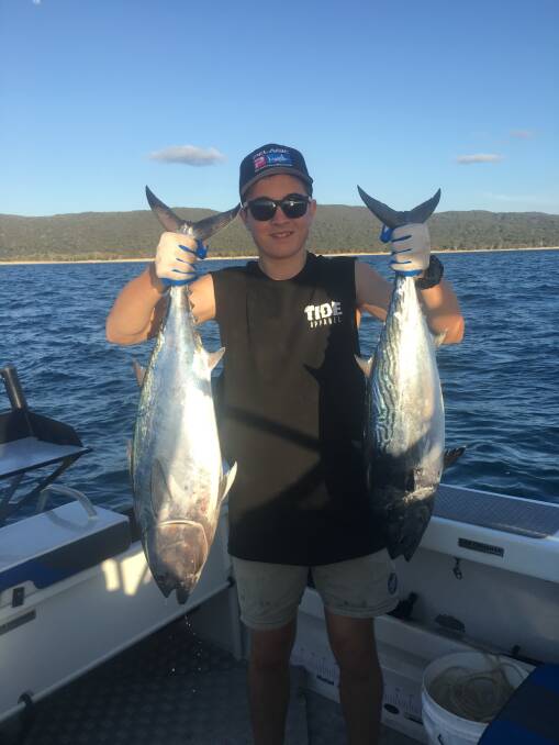 Ethan Hall with his hands full of longtail tuna caught on lures inside Moreton Island.