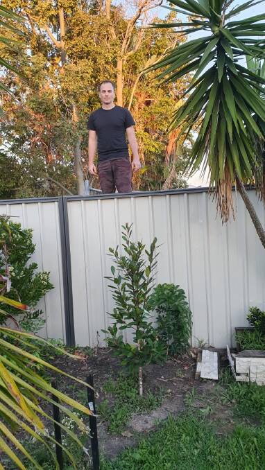 Matthew Hansen shows the height of the property next door.