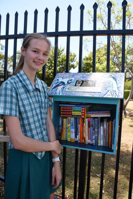Year 8 student Bianca Langham takes a closer look at the books in the Wellington Point State High School street library.