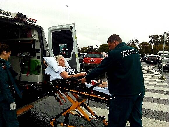IN THE RAIN: Sandra Mckeown being wheeled into an ambulance at the Weinam Creek marina bus station.