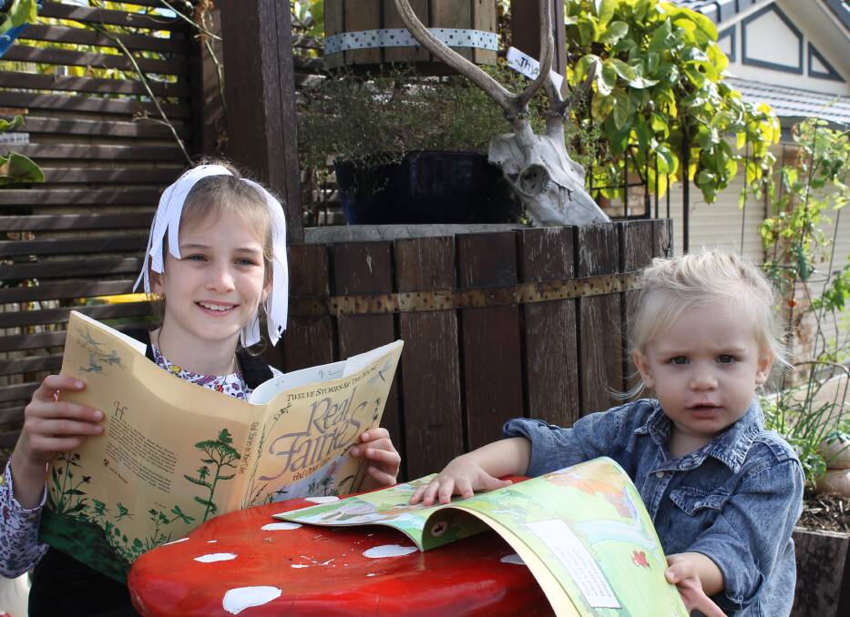IN FAIRY LANE: Sophia Van-Lint, 8, and Axel Morgan, 2, read books from the street library while sitting on toadstolls in the Fairy Lane garden at Capalaba. Photo: Cheryl Goodenough