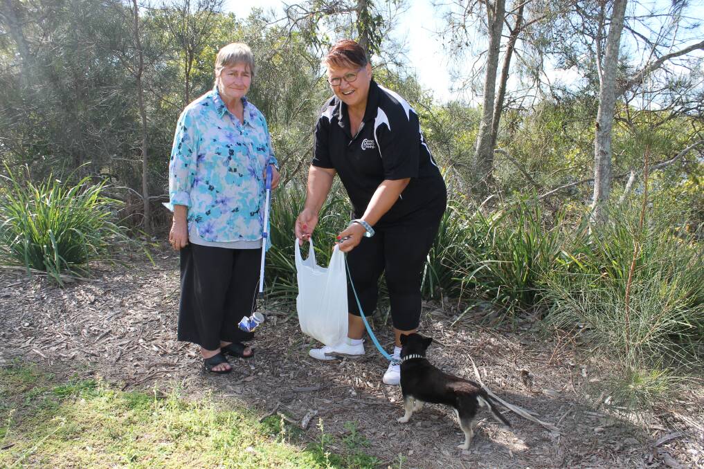 PICKING UP: Diann Briscoe and Lily Edwards pick up rubbish at a Redland Bay park. They are accompanied by Ms Edwards' dog Meca. Photo: Cheryl Goodenough