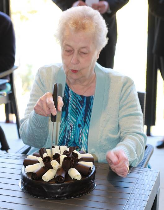 Moreton Shores resident of six years Clare McKirdy cuts the cake at the opening.