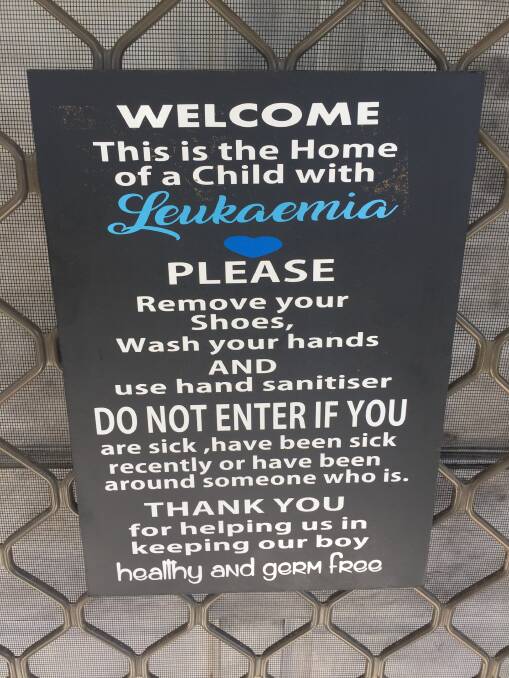 REQUEST: A sign on the Mitchell's front door asks anyone who has been sick or around someone who is sick to stay away to help keep Eddie healthy and germ free.