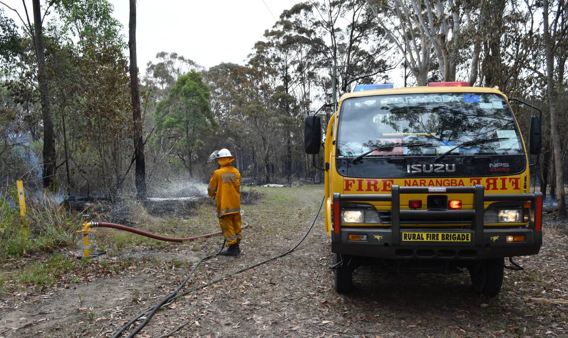 ON RUSSELL ISLAND: Rural Fire Service volunteer Lee Goodsell douses smouldering scrub in water in 2016. Photo: Hannah Baker