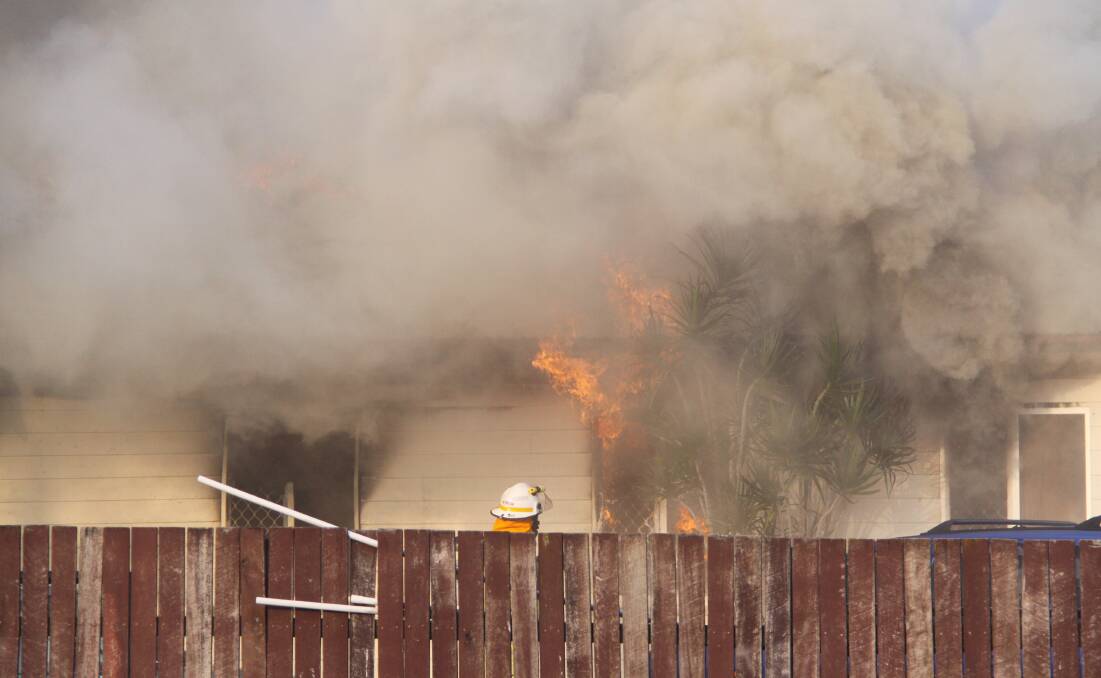HOUSE FIRE: A firefighter working to put out a blaze at a Birkdale house on Sunday. Photo: Grant Spicer