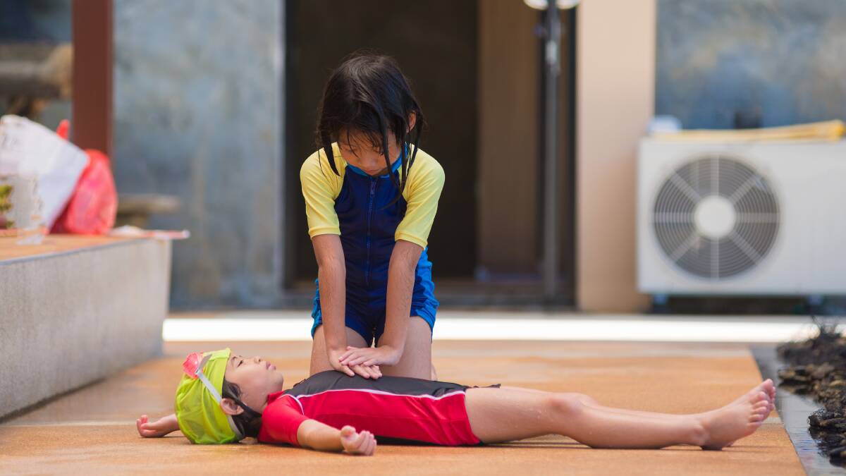 A child illustrates a CPR technique.