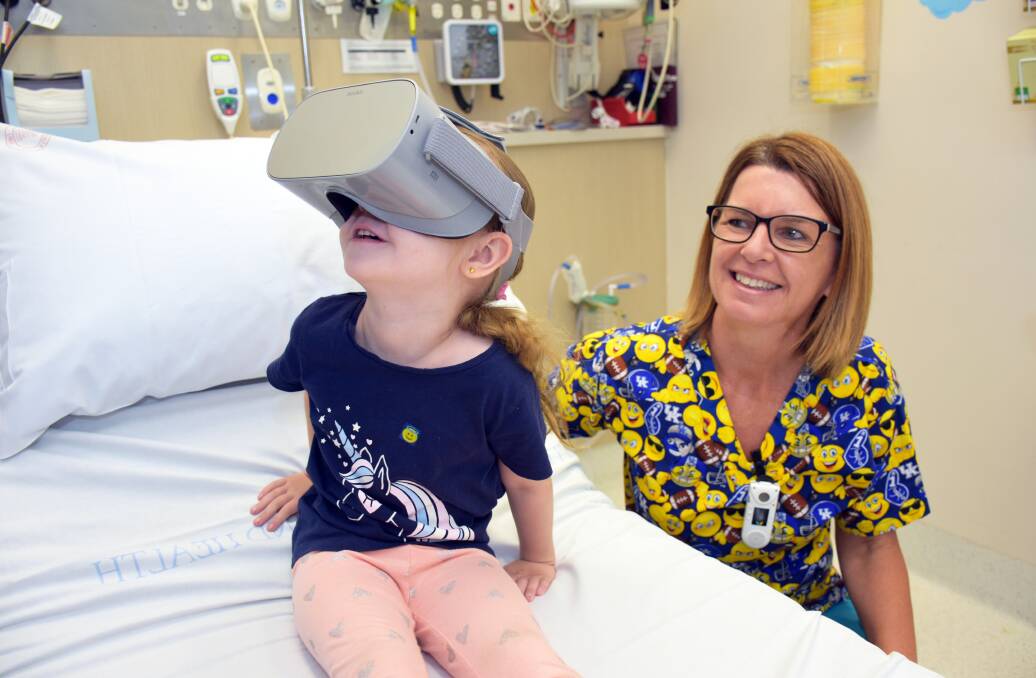 Alexandra Hills girl Sabrina, 5, is taken on a fun journey while wearing virtual reality goggles, with nurse Katrina Adams. Photo: Supplied 