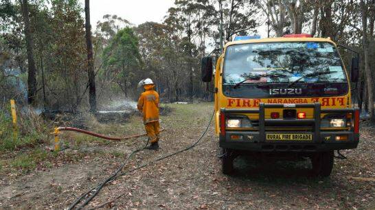 BLAZE: A Rural Fire Service volunteer douses smouldering scrub in water at Russell Island. Photo: Hannah Baker