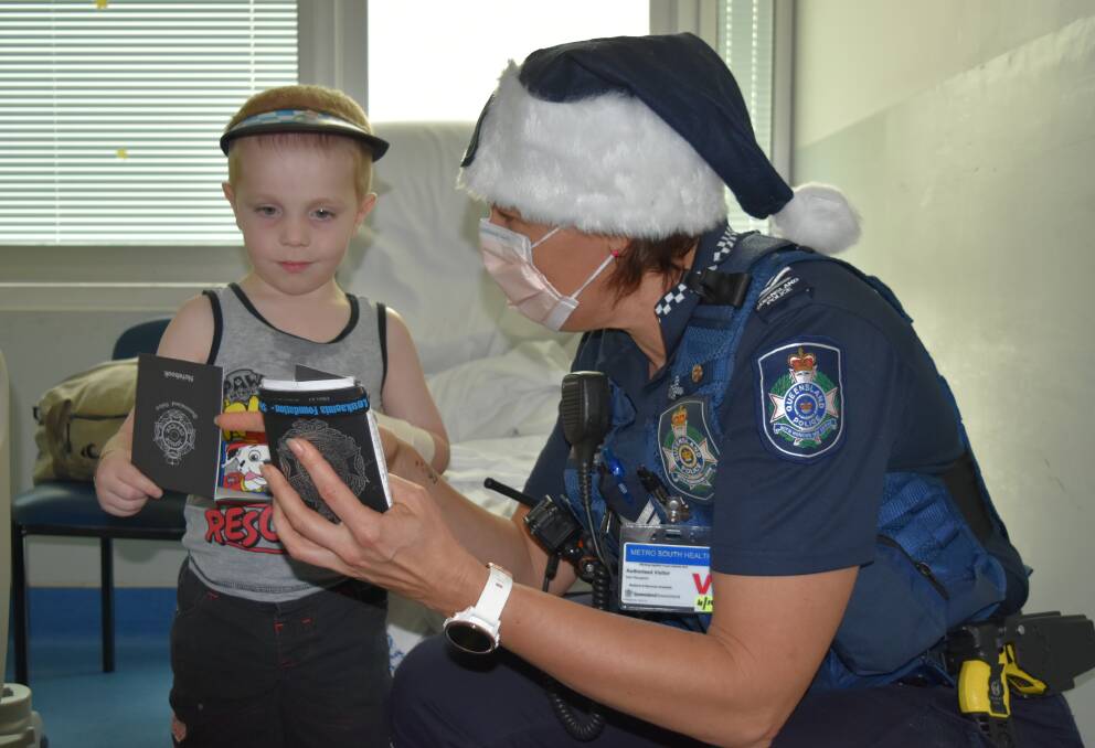 Redland Hospital patient Jack Tognola, 4, and Senior Constable Nicole Jackson compare note pads. Photo: Hannah Baker 