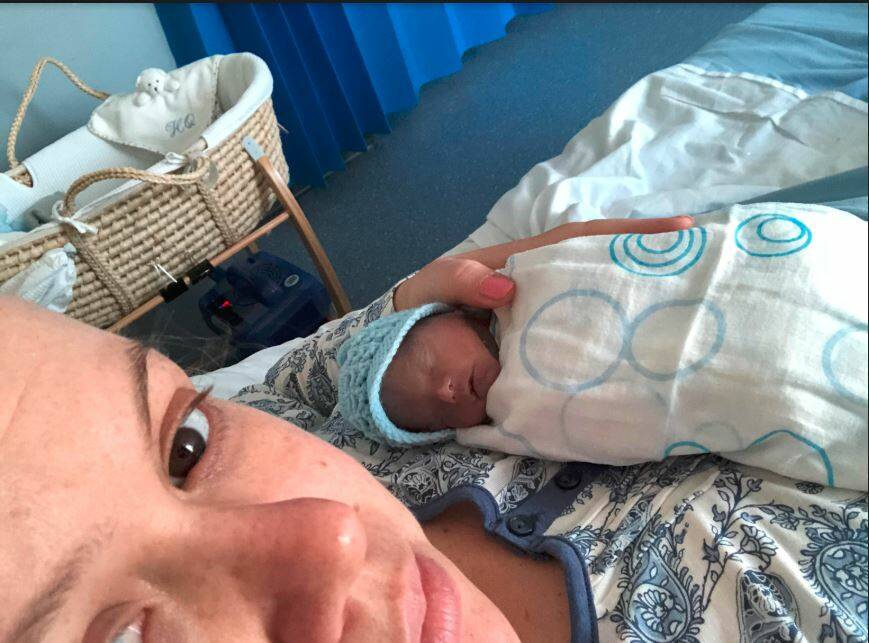 Ms Quinn holds her son Harry. A bassinet cooled by a CuddleCot is pictured in the background. Photo: Supplied